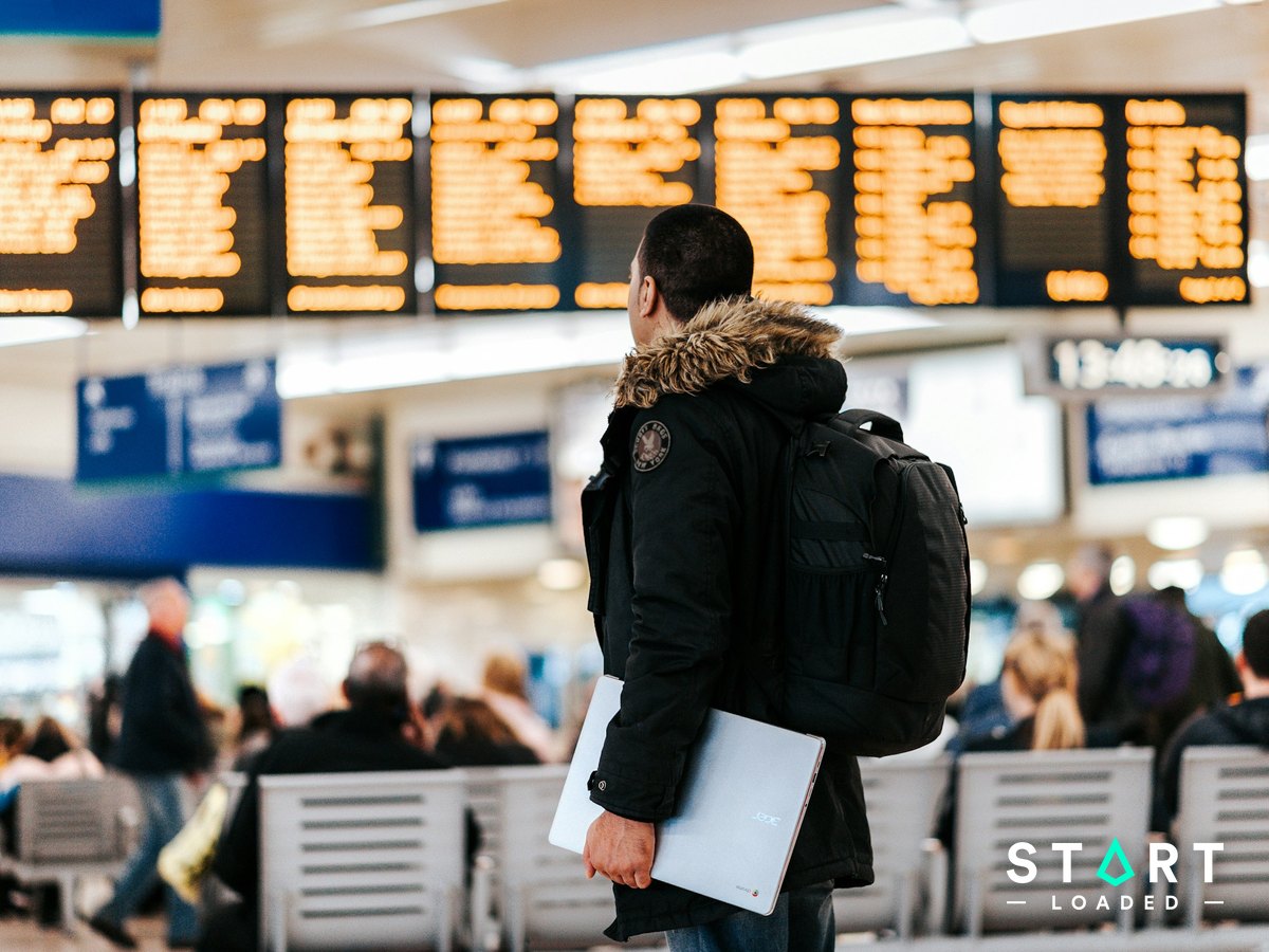 Traveller with a backpack looking at the departures board in an airport