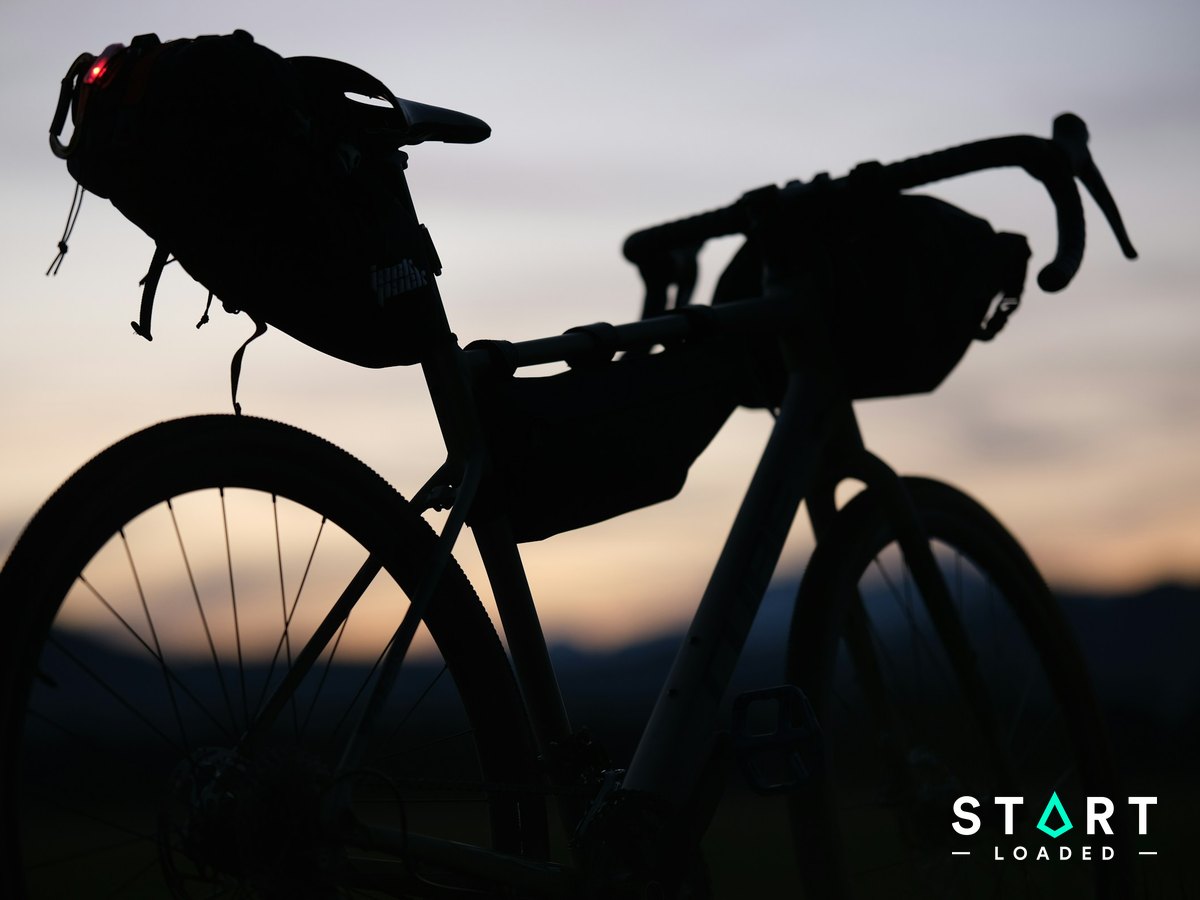 Silhouette of a touring bike loaded with bikepacking bags at sunset