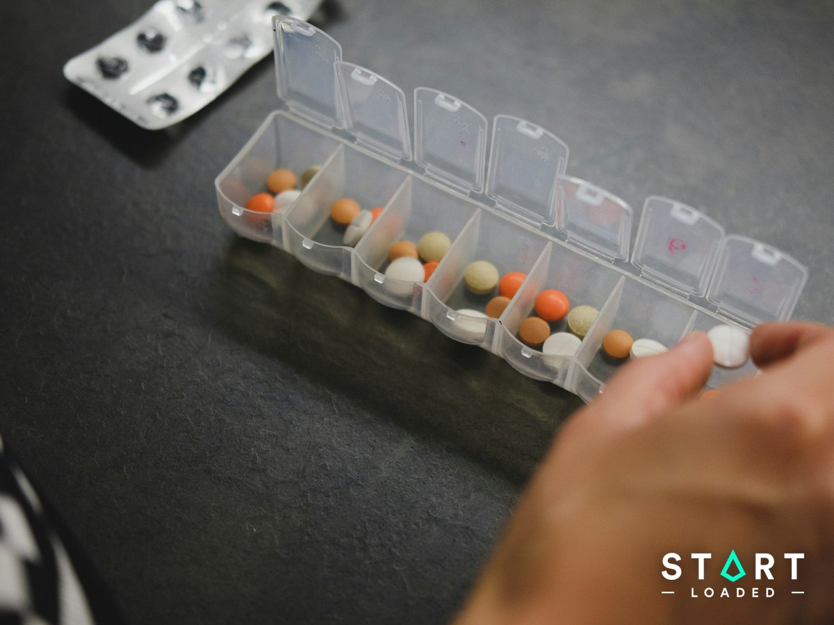 Hand picking tablets from a weekly pill organiser