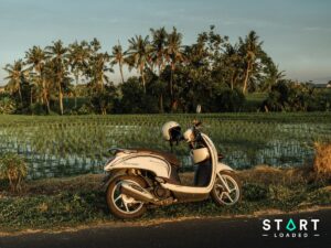Scooter with a helmet on the mirror parked beside rice fields in Bali