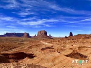 Empty desert road leading towards the red rock buttes of Monument Valley in Utah